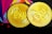 Two golden coins with the abbreviation 'EXU' engraved on them, surrounded by abstract colorful shapes in the background. The coins have detailed engravings, featuring animals and patterns along the edges.