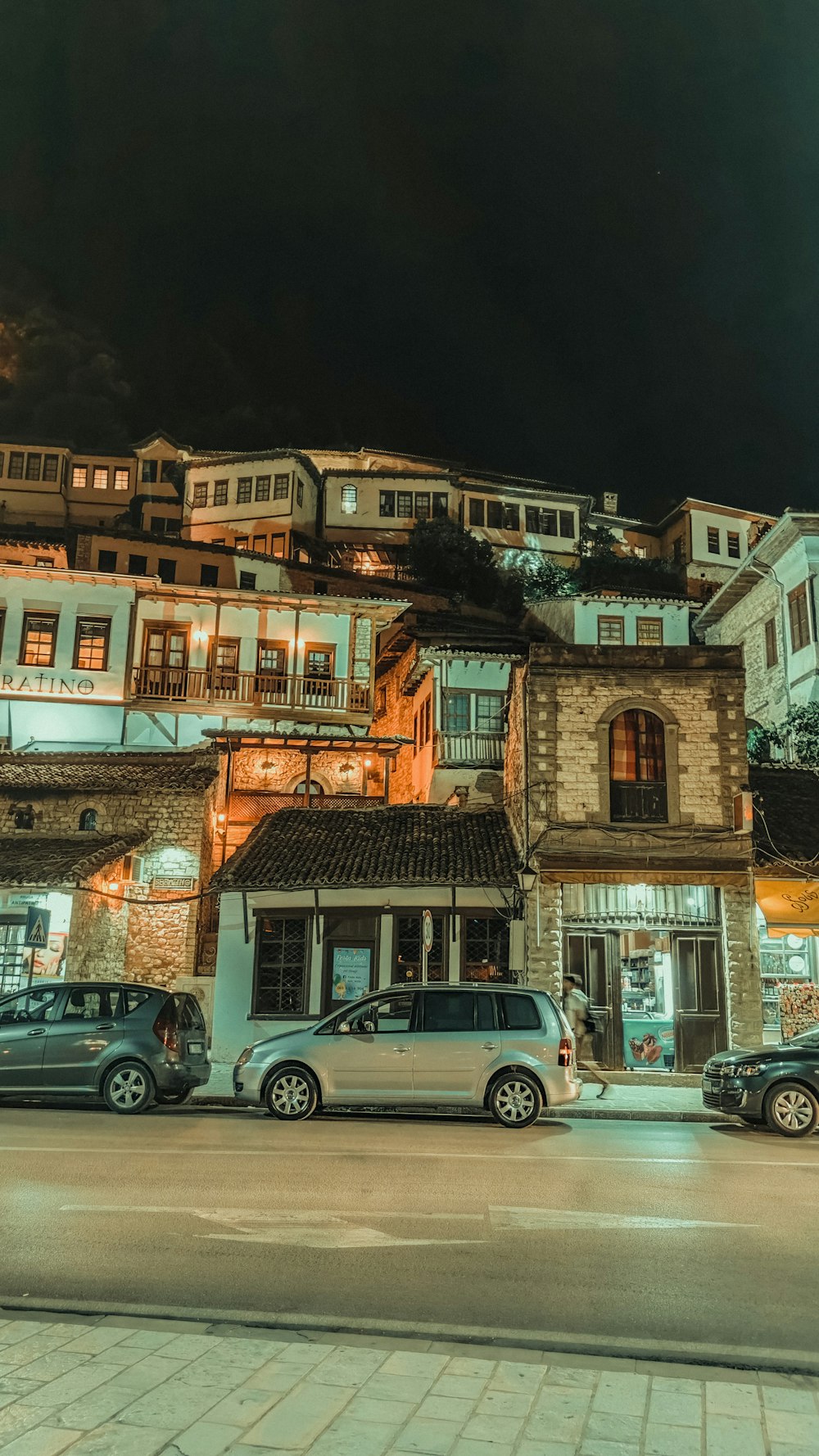 cars parked in front of brown concrete building during night time