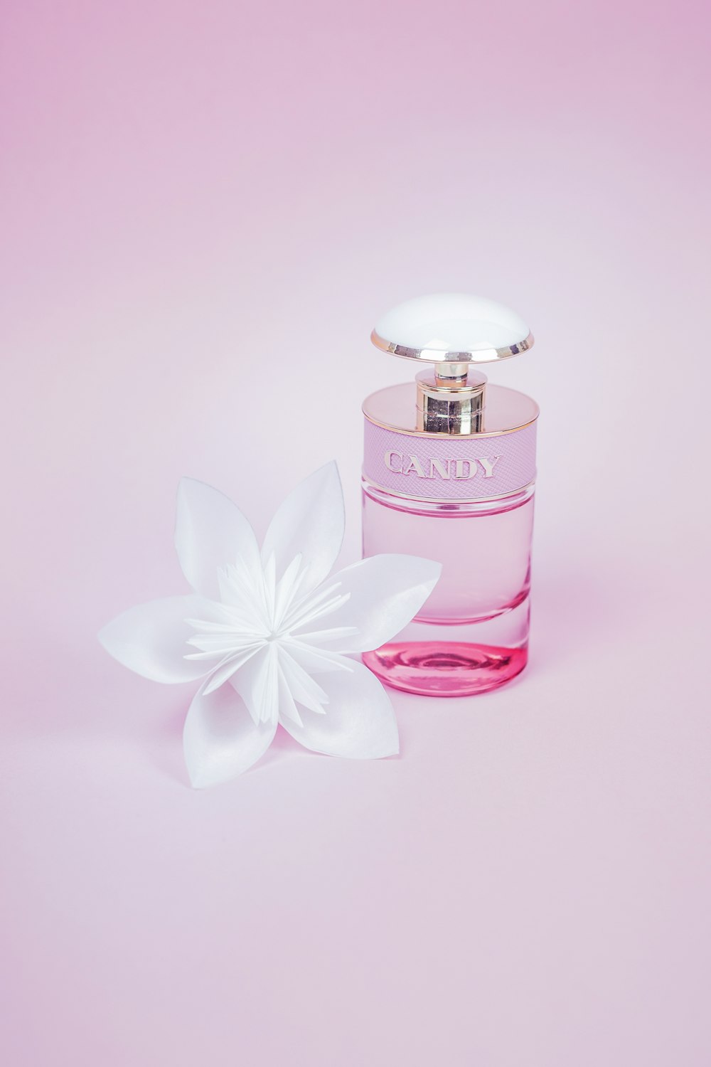 frasco de perfume rosa com flor branca