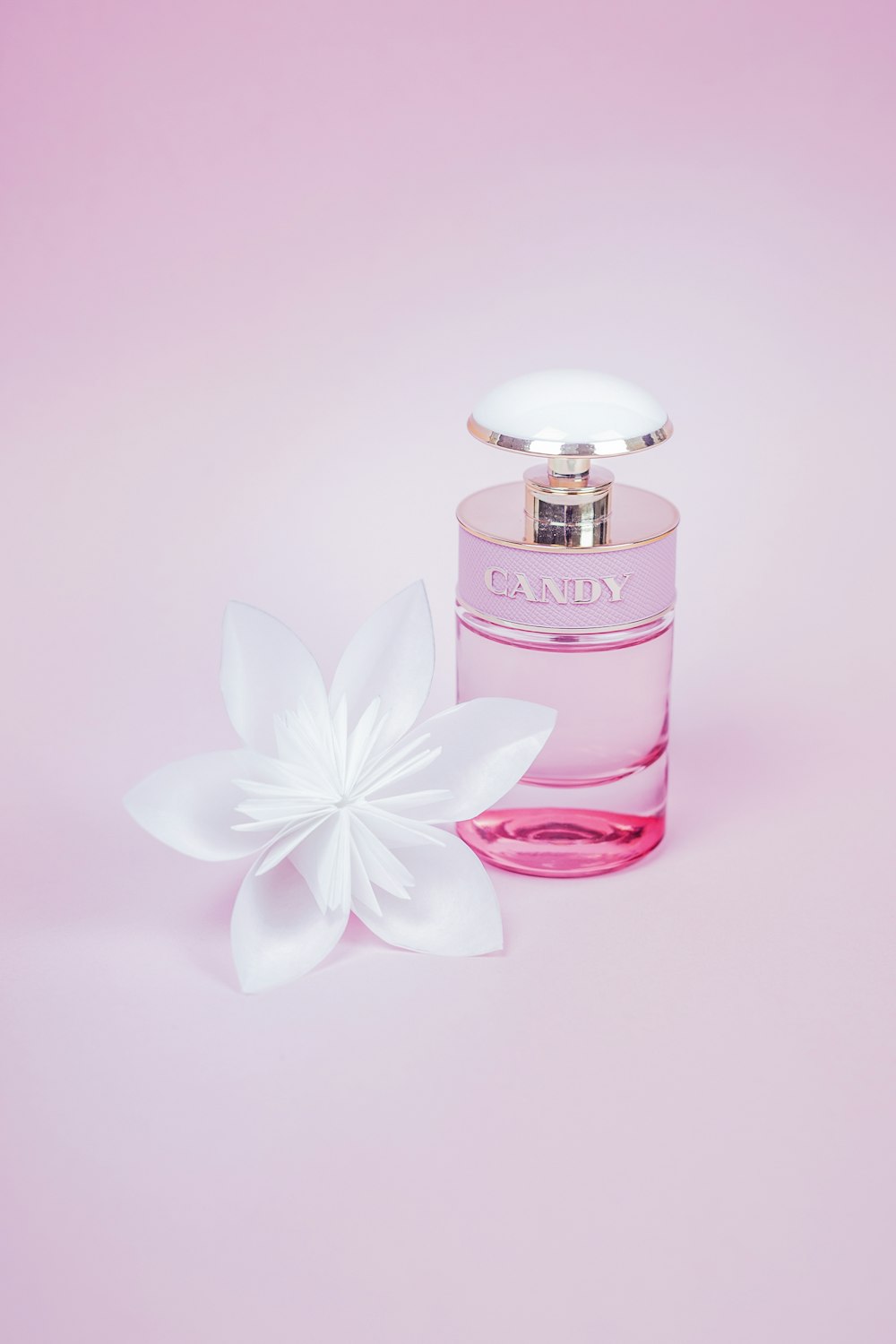 Frasco de perfume rosa con flor blanca