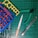 A collection of hobby tools and plastic model parts arranged on a green cutting mat with a grid pattern. The items include plastic model sprues in blue, red, and yellow, a metal file with an orange handle, green-handled clippers, and a utility knife.