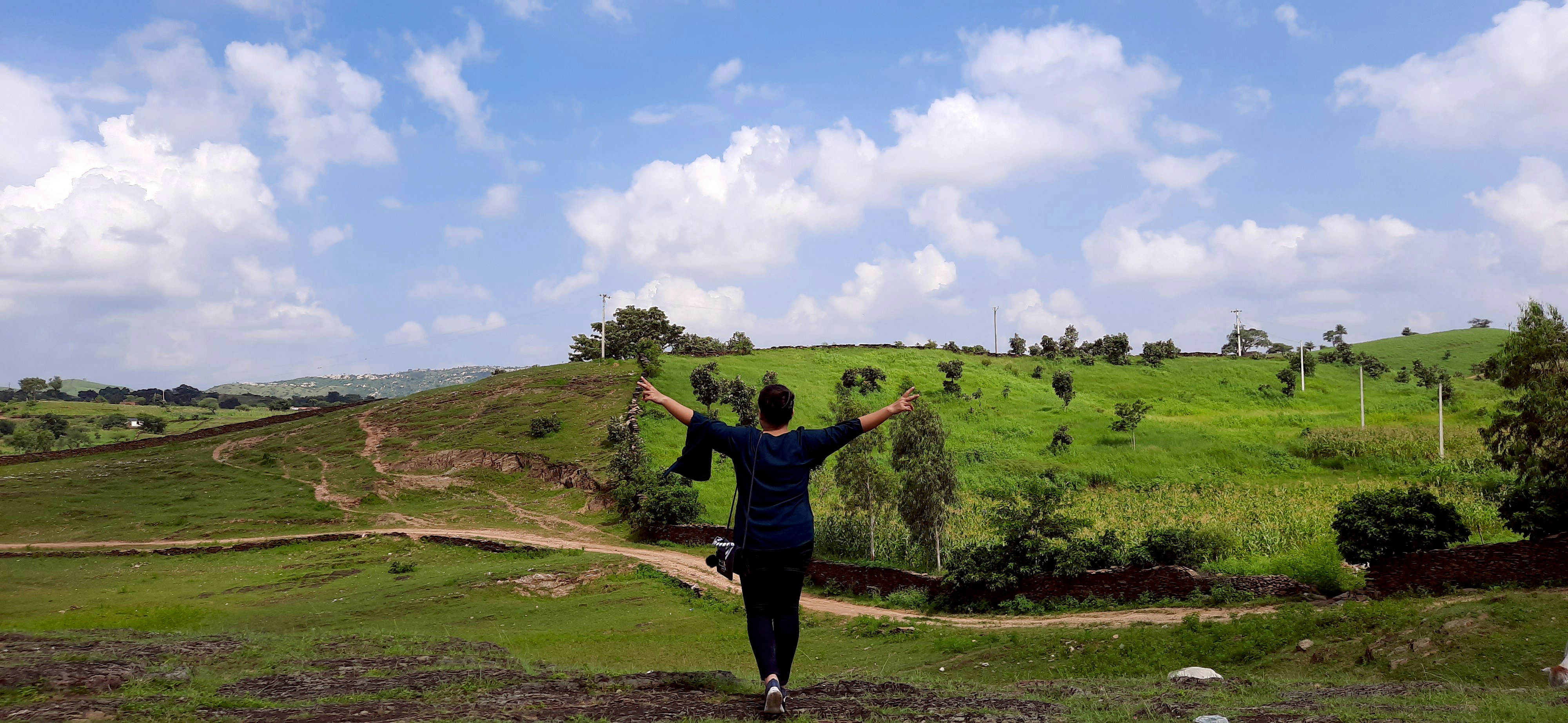 woman in black long sleeve shirt and black pants standing on green grass field under blue 풍경 사진