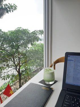 A cozy workspace with a laptop displaying Vietnamese news articles on screen.