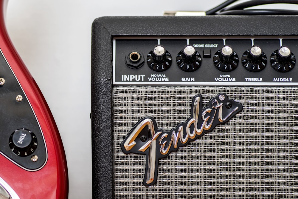 a red guitar and a black amp sitting next to each other