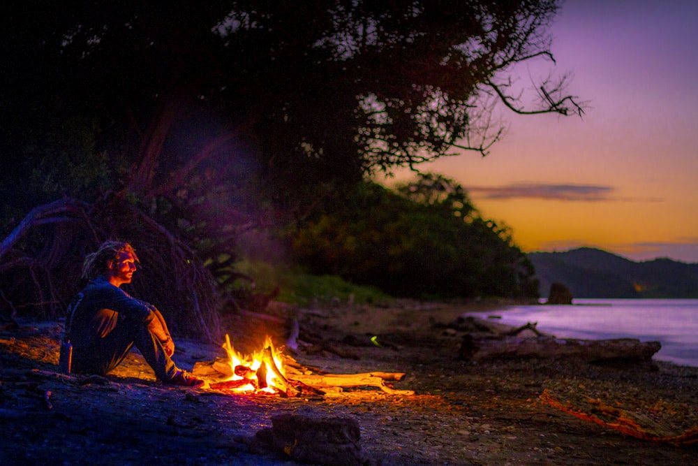 man sitting on ground near bonfire during night time