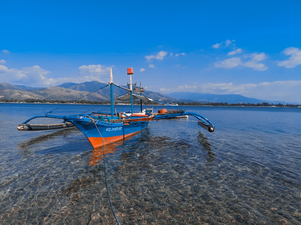 orange and white boat on sea under blue sky during daytime