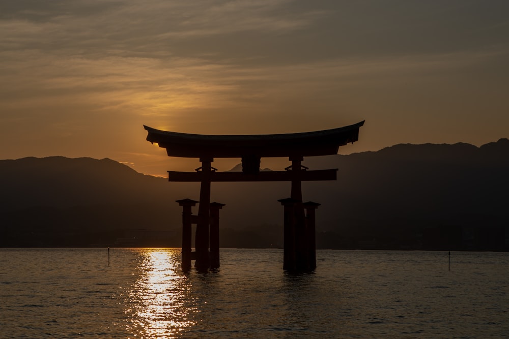 silhouette of a person standing on a wooden stand in the middle of a sea during