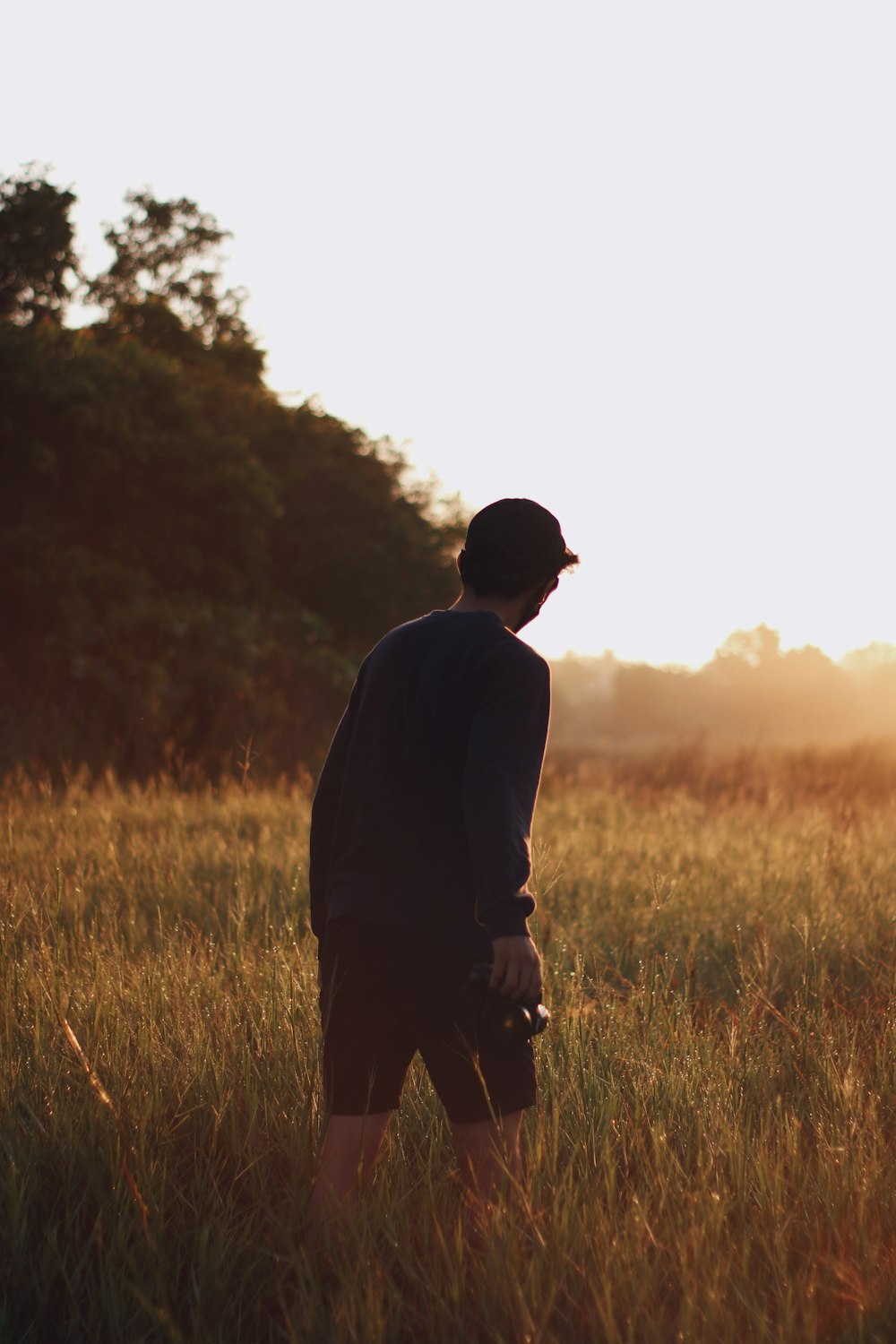 man in black jacket walking on green grass field during daytime