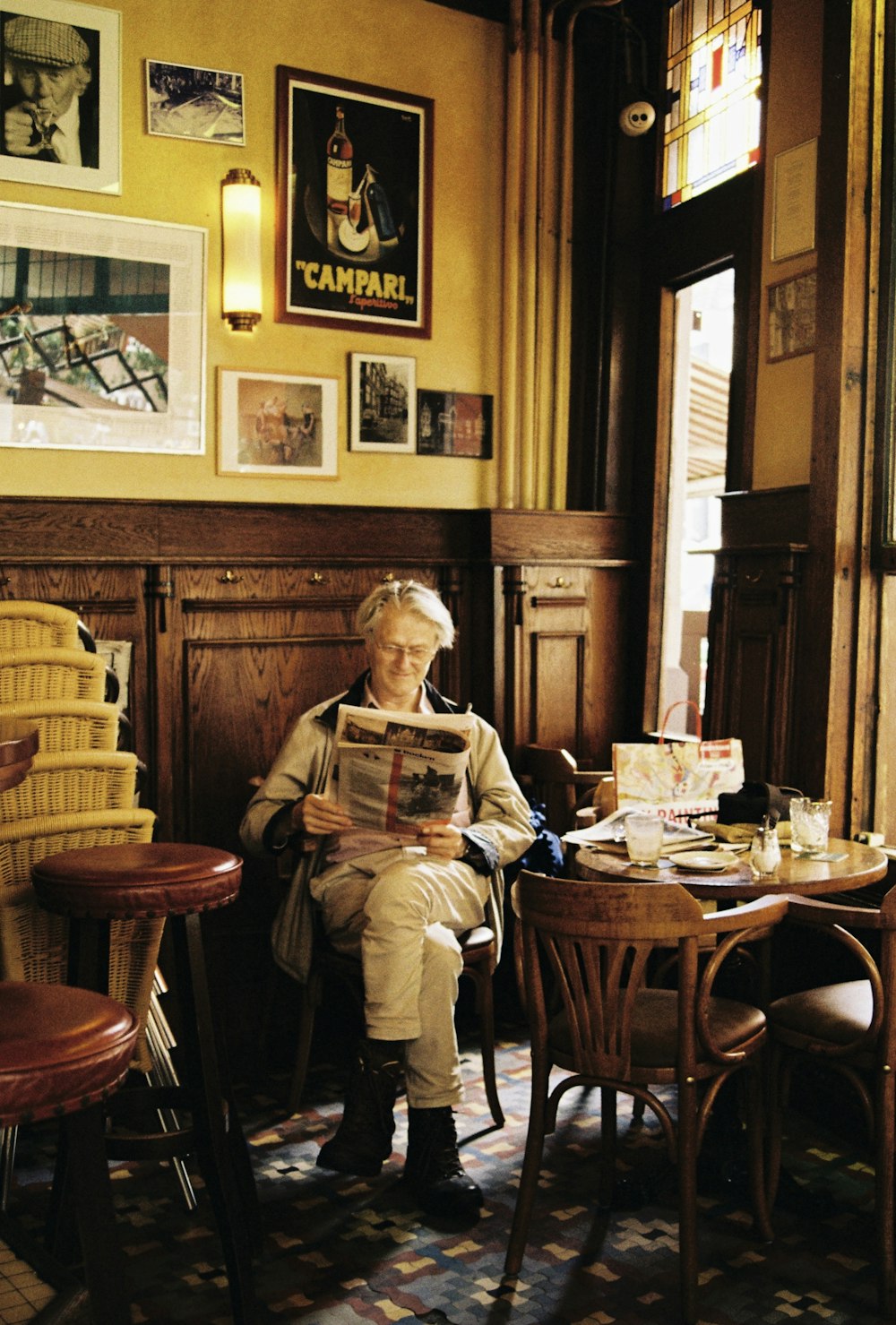 man in brown jacket sitting on chair reading newspaper