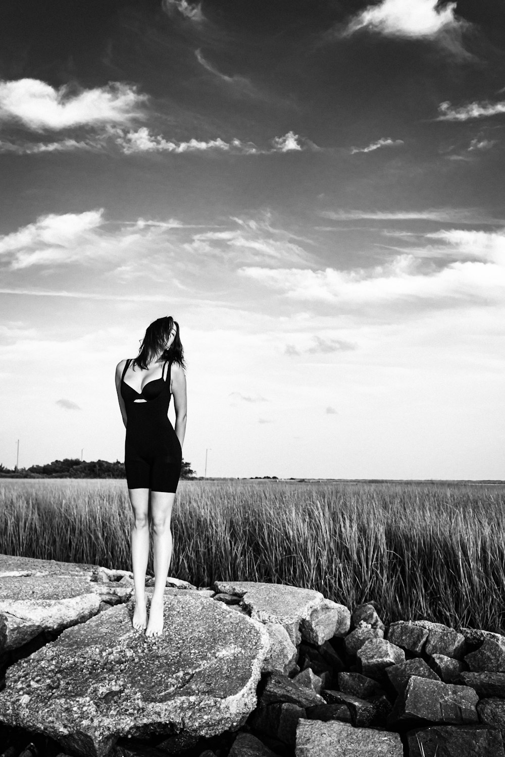 woman in black tank top and white pants standing on gray rock