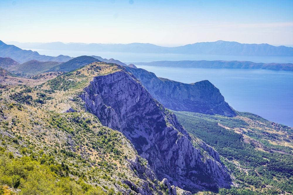 green and gray mountain near body of water during daytime