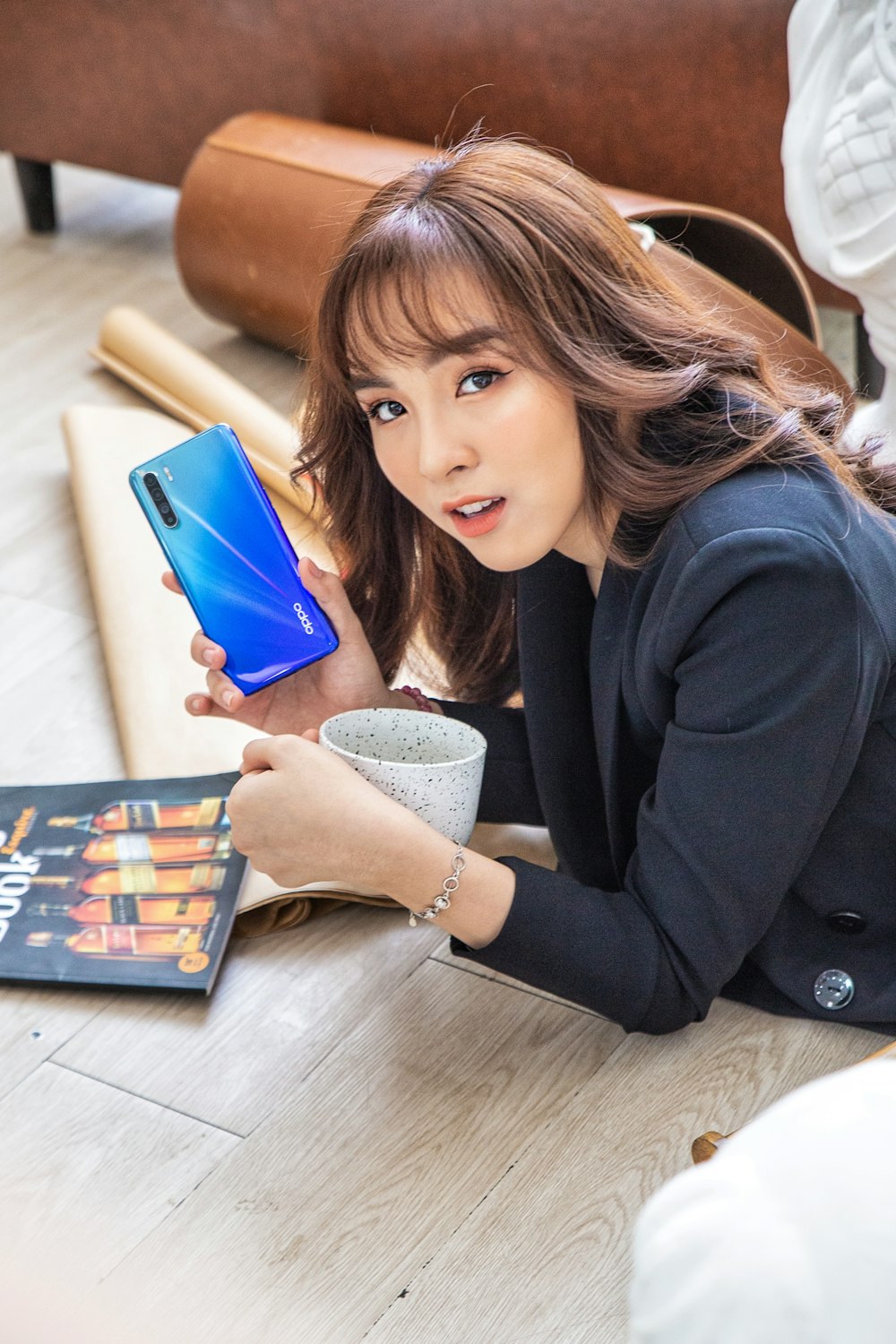 Frau in schwarzem Blazer mit blauem Smartphone