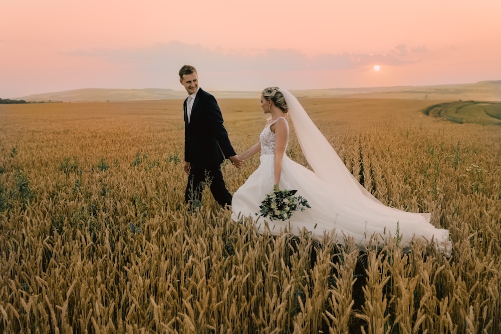 man in black suit and woman in white wedding dress on green grass field during daytime