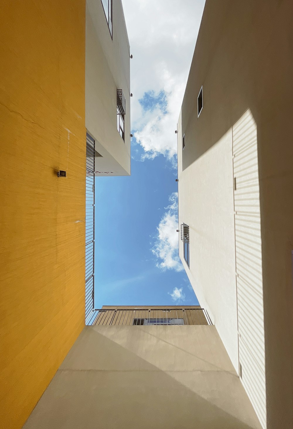 worms eye view of white concrete building under blue and white sunny cloudy sky during