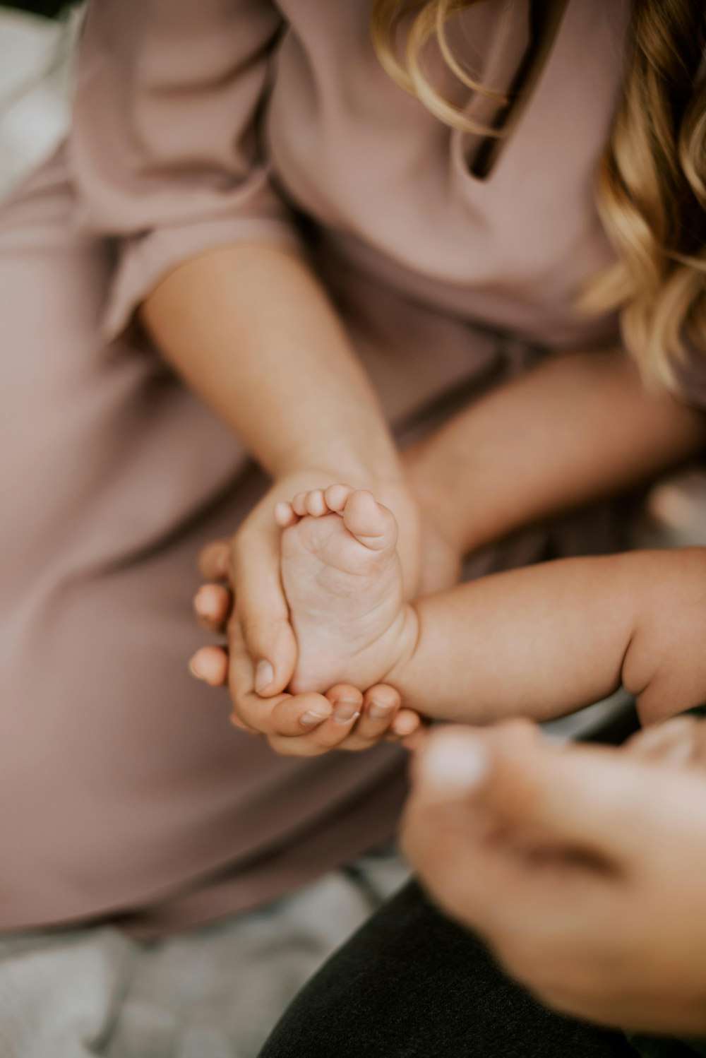 woman in white tank top holding babys hand