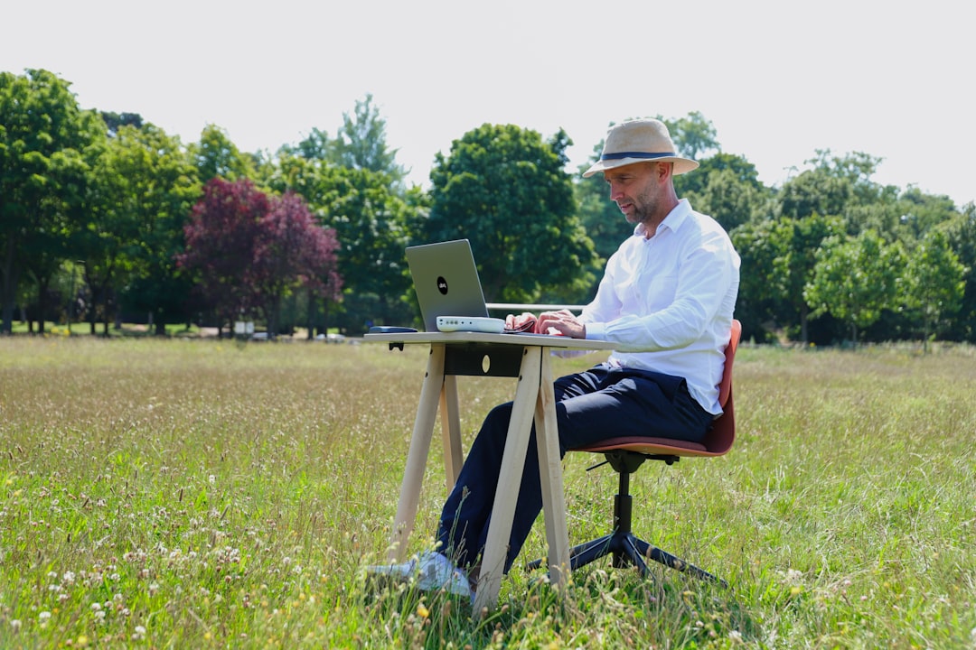 man in white dress shirt sitting on chair using laptop computer
