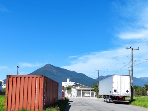 A Meditrans container truck driving along a scenic highway outside Montreal, with mountains in the background.