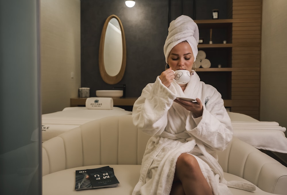 woman in white robe sitting on white couch