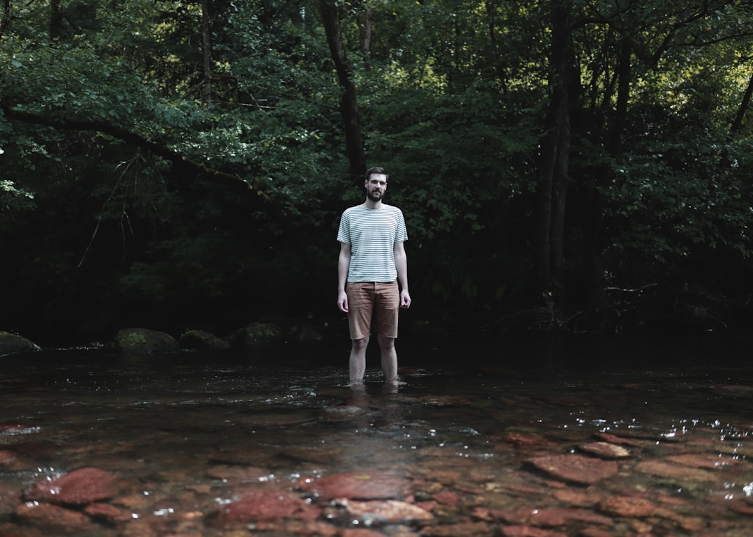 man in white dress shirt and gray pants walking on brown pathway in forest during daytime