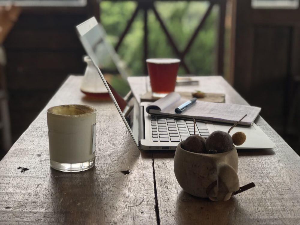 silver macbook pro beside white ceramic mug on brown wooden table