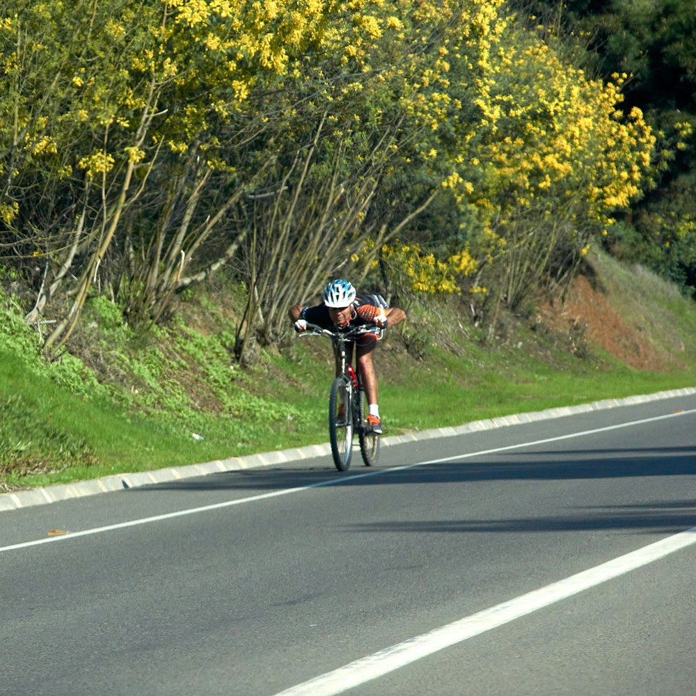 man in black and white shirt riding bicycle on gray asphalt road during daytime