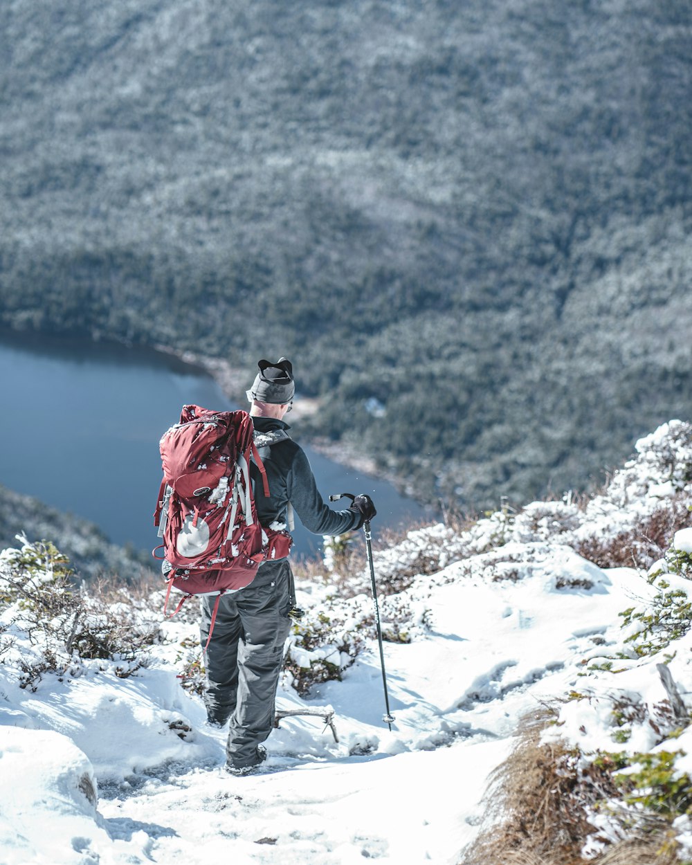 person in red jacket and white pants standing on snow covered mountain during daytime