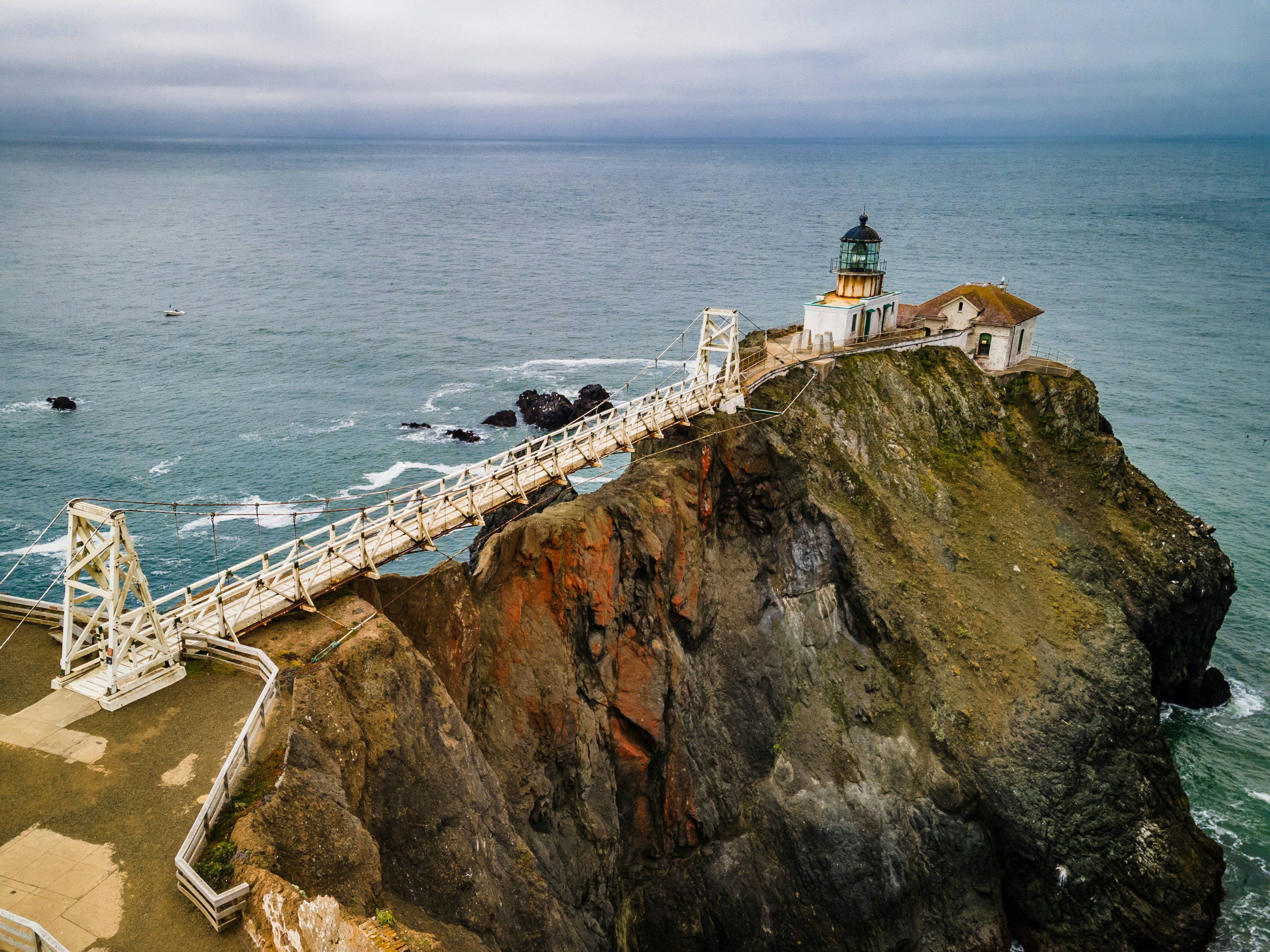 white and brown concrete building on brown and green mountain beside sea during daytime