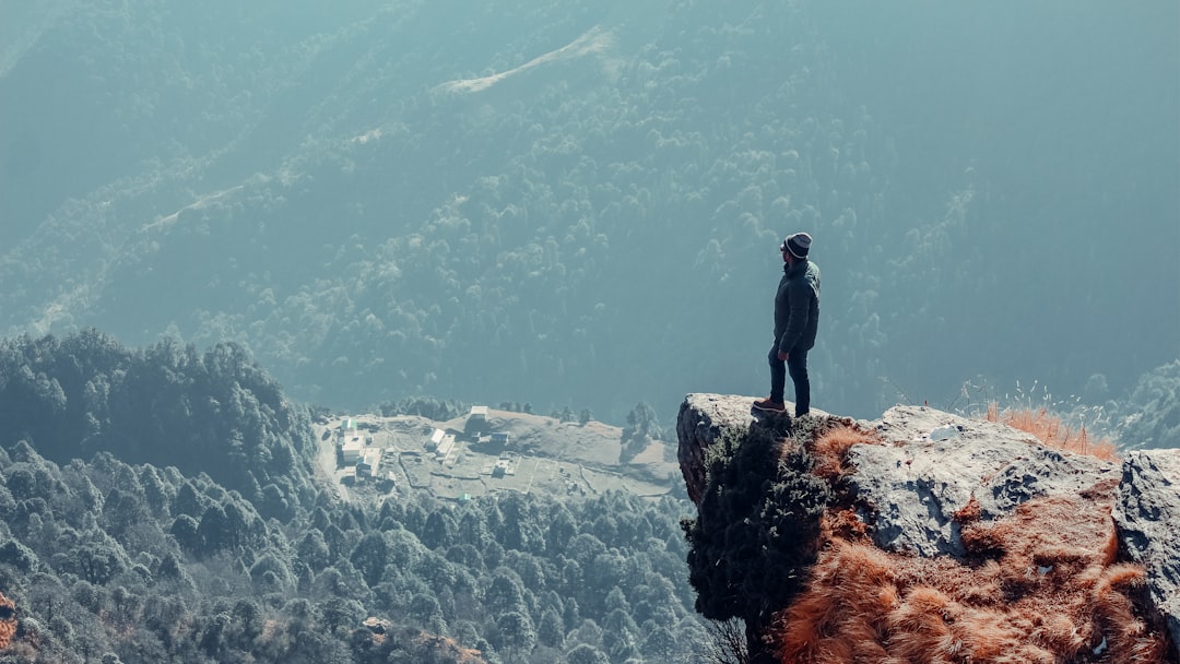 man in black jacket standing on rock formation during daytime