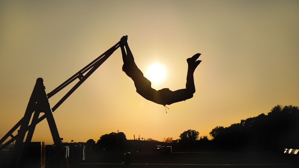 silhouette of person jumping on air during sunset
