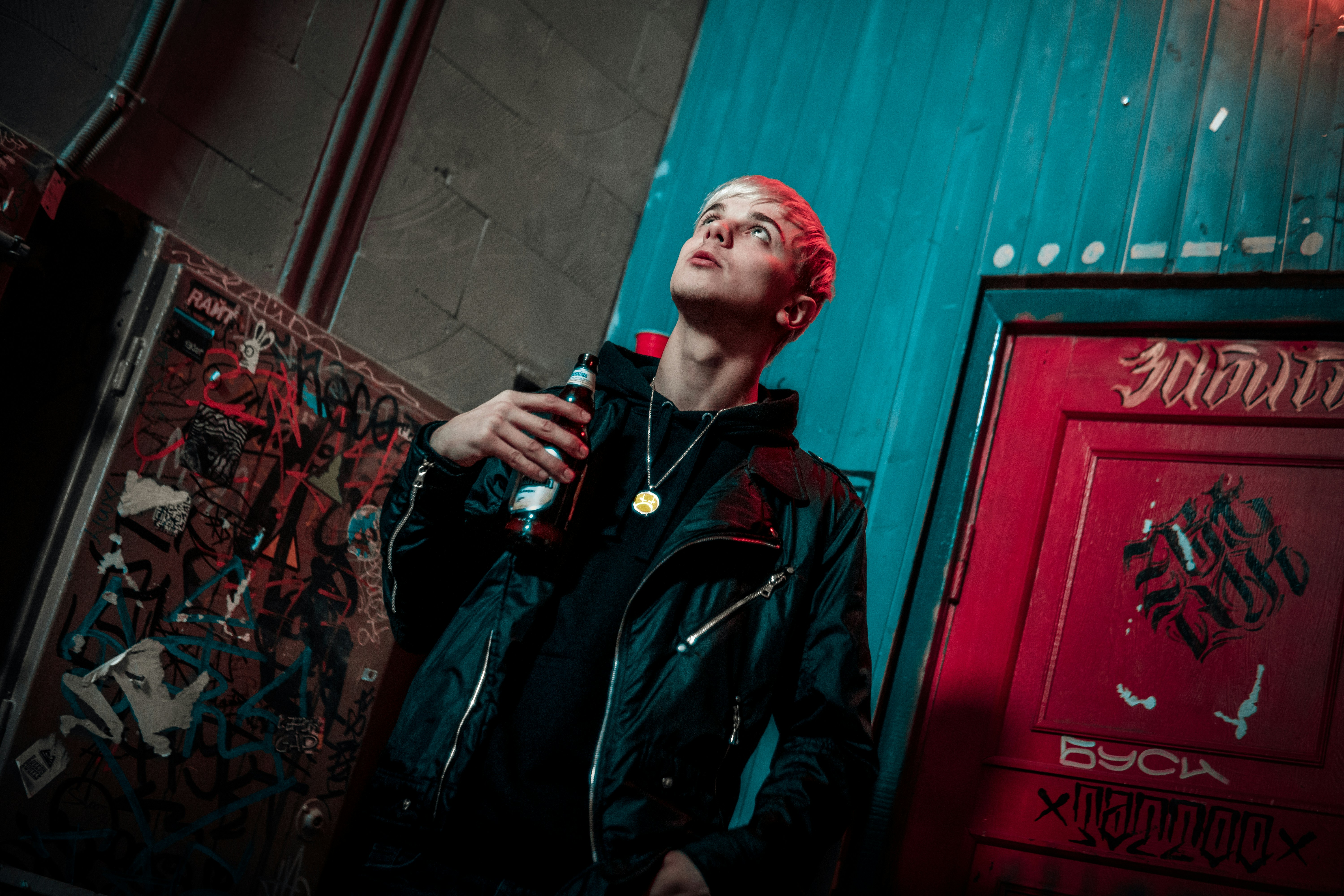 man in black leather jacket holding bottle