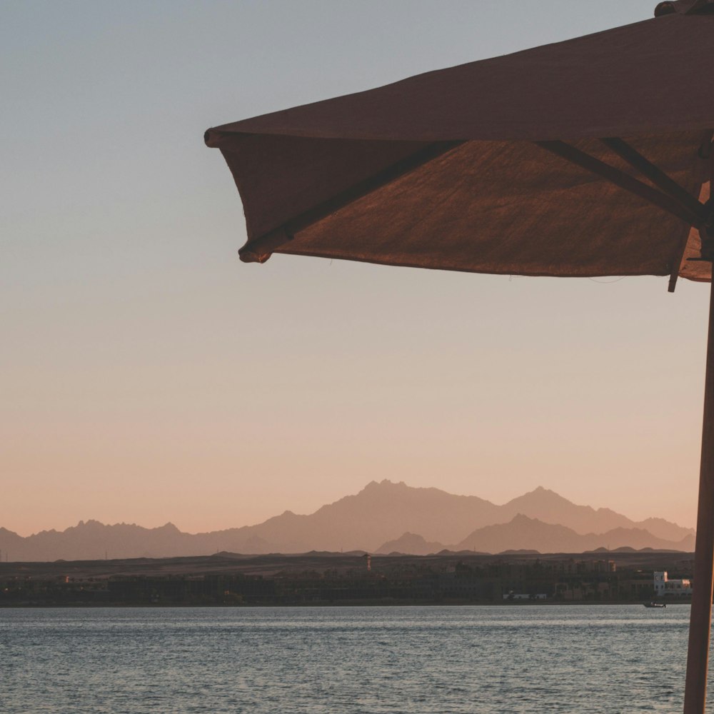 brown umbrella near body of water during daytime