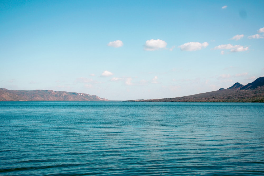 blue sea near mountain under blue sky during daytime