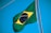 A Brazilian flag is waving against a clear blue sky. The flag includes a green field with a yellow diamond in the center, which encases a blue circle adorned with white stars and the motto 'Ordem e Progresso'.