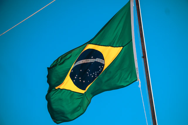 A vibrant Brazilian flag waving proudly against a clear blue sky.