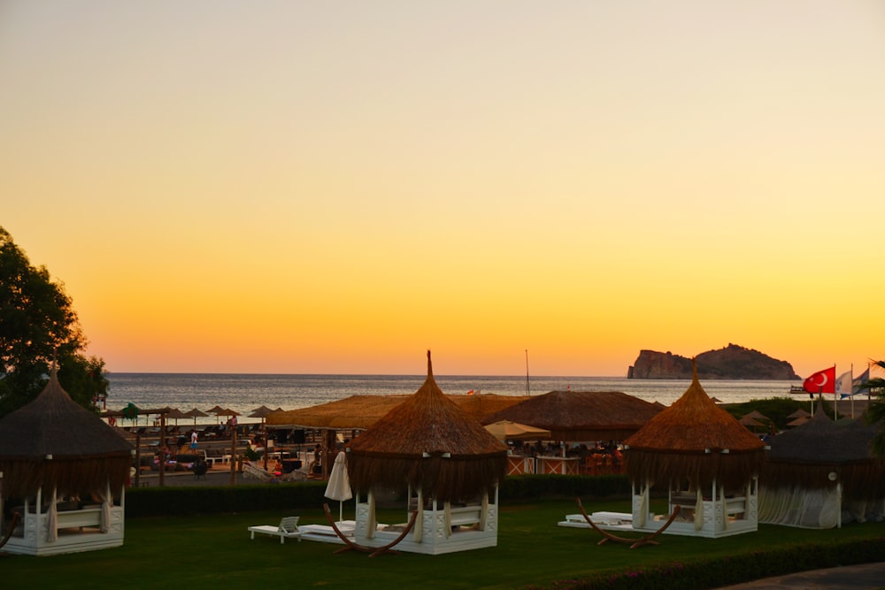 casa marrom e branca perto do corpo de água durante o pôr do sol