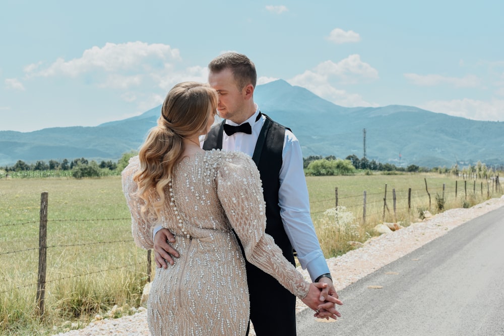 man in black suit holding woman in brown dress on road during daytime