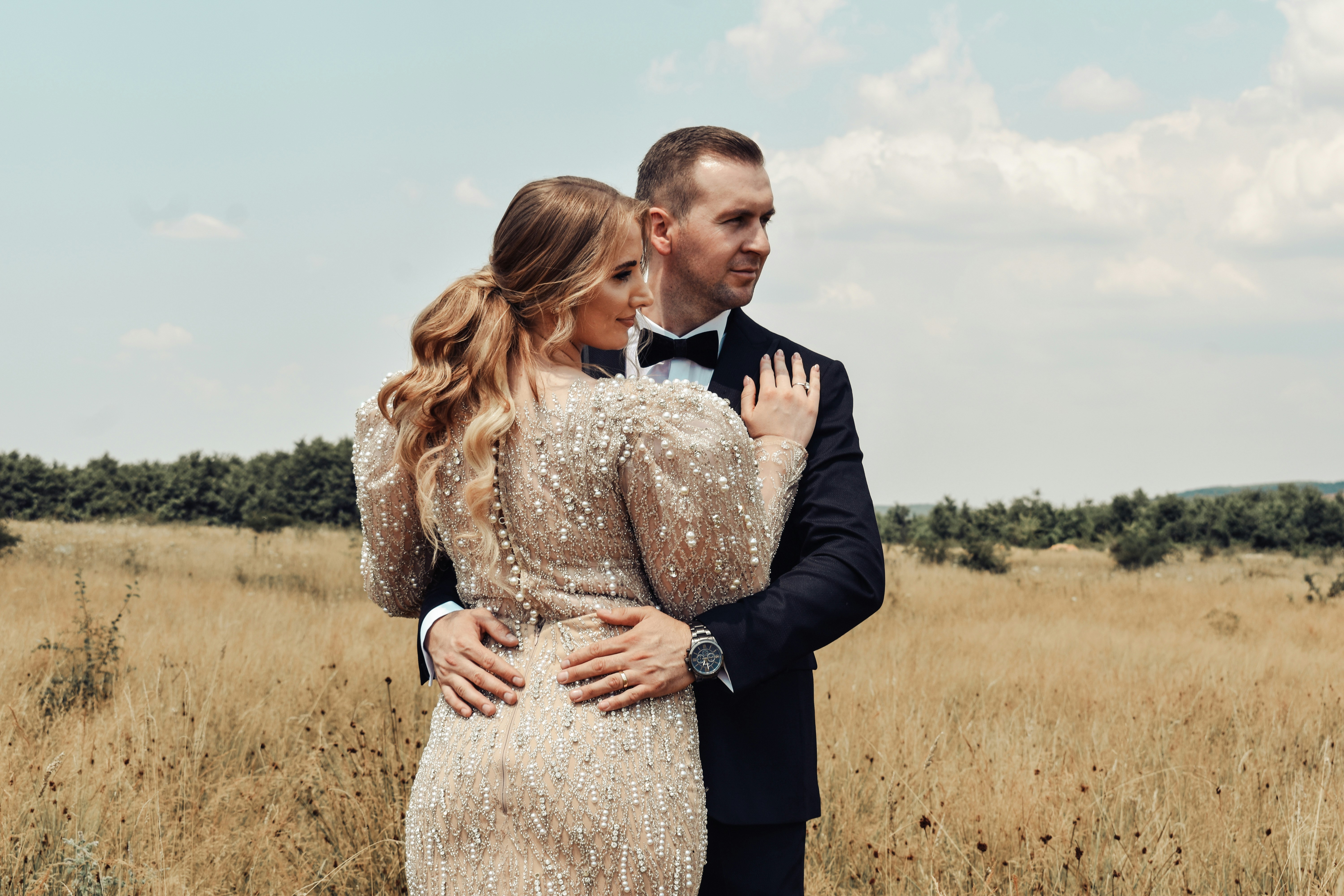 man in black suit jacket hugging woman in white dress