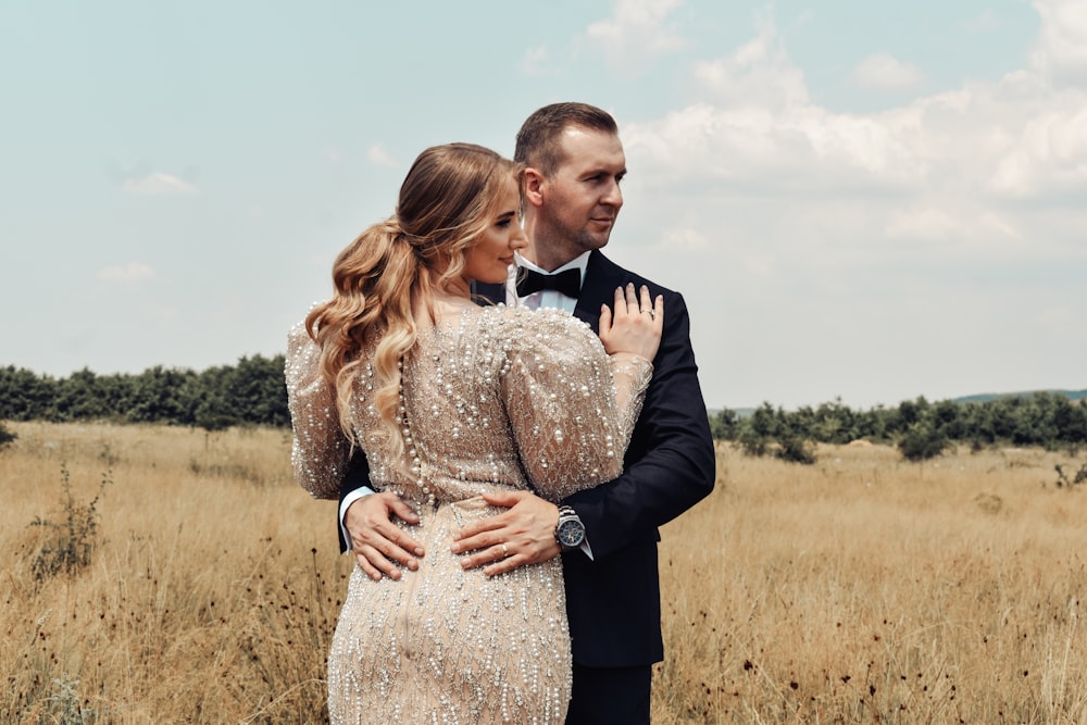 man in black suit jacket hugging woman in white dress