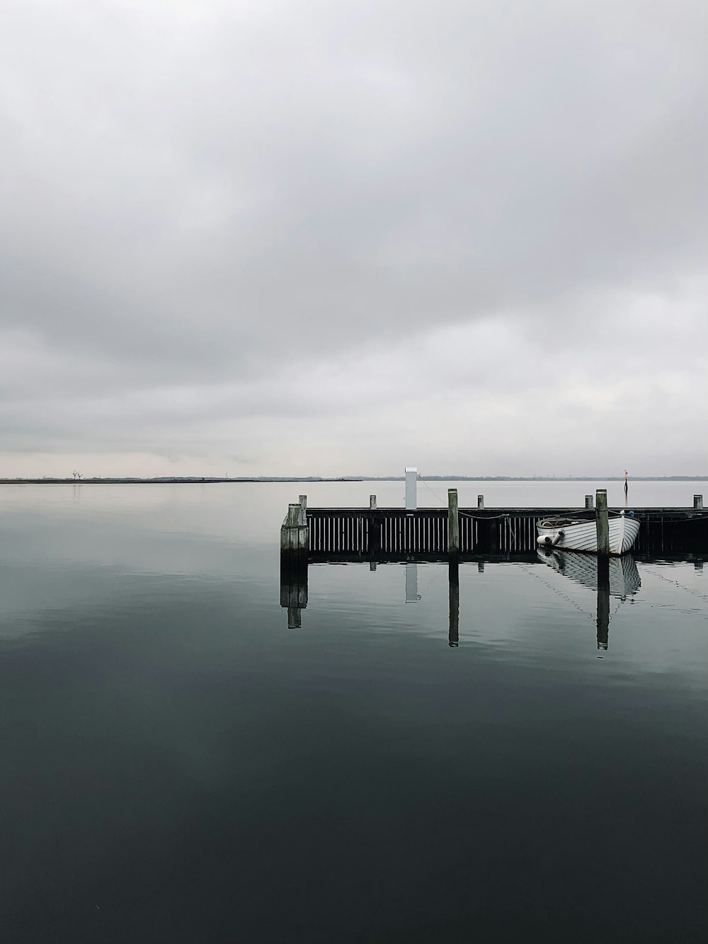 dock on calm water under gray clouds