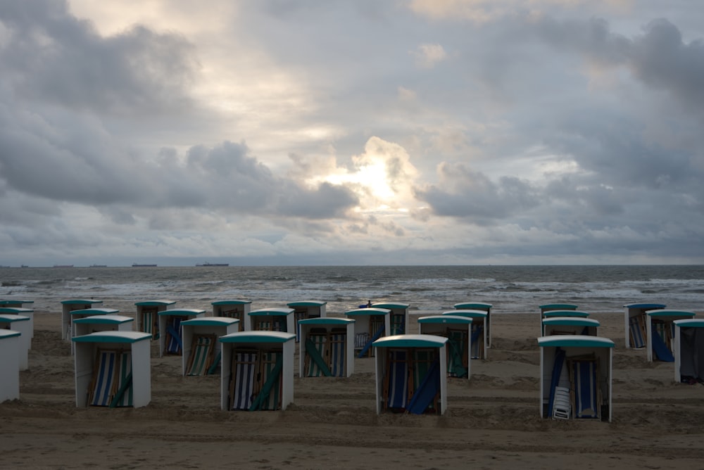 green and blue trash bins on beach under cloudy sky during daytime