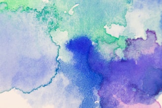 Abstract watercolor painting featuring a blend of soft blue, green, and purple hues, providing a soothing and artistic texture.