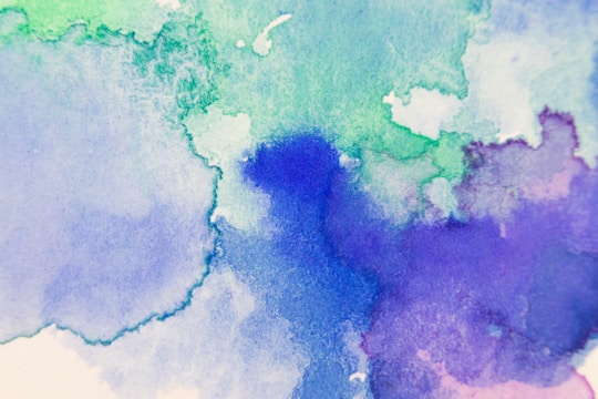 Abstract watercolor painting featuring a blend of soft blue, green, and purple hues, providing a soothing and artistic texture.