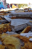 A pile of rubble consisting of broken concrete slabs and large pieces of yellow insulation material. In the background, there are colorful graffiti-covered walls, adding an urban and abandoned feel to the scene.