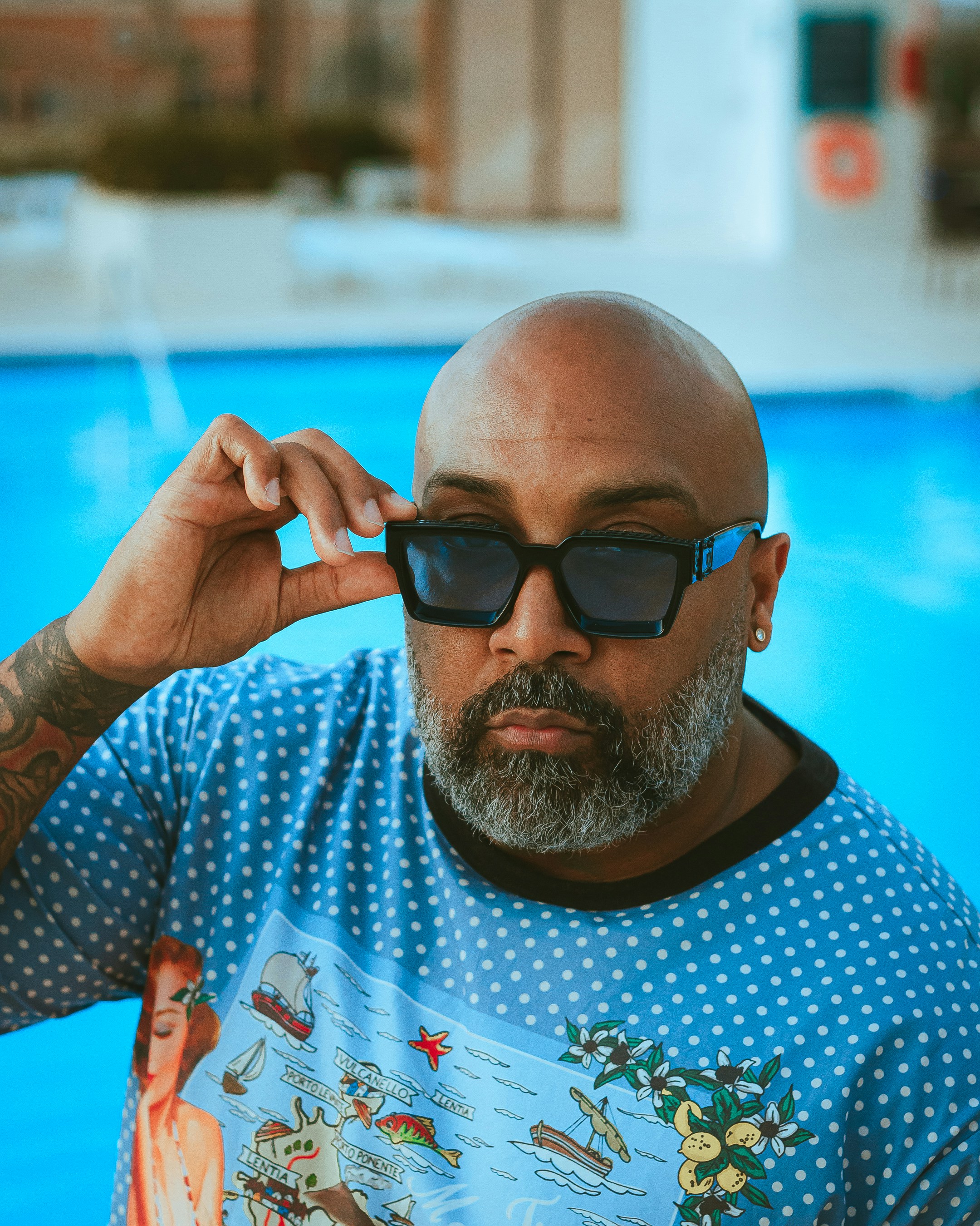 Homme en chemise à col rond bleu et blanc portant des lunettes de soleil noires