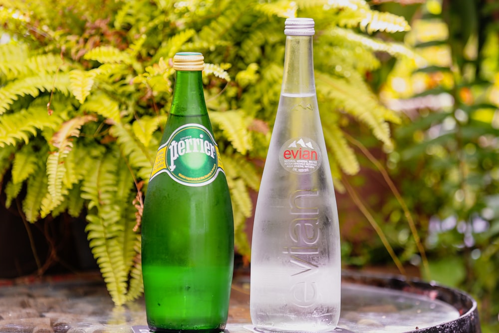 two green glass bottles on brown wooden table