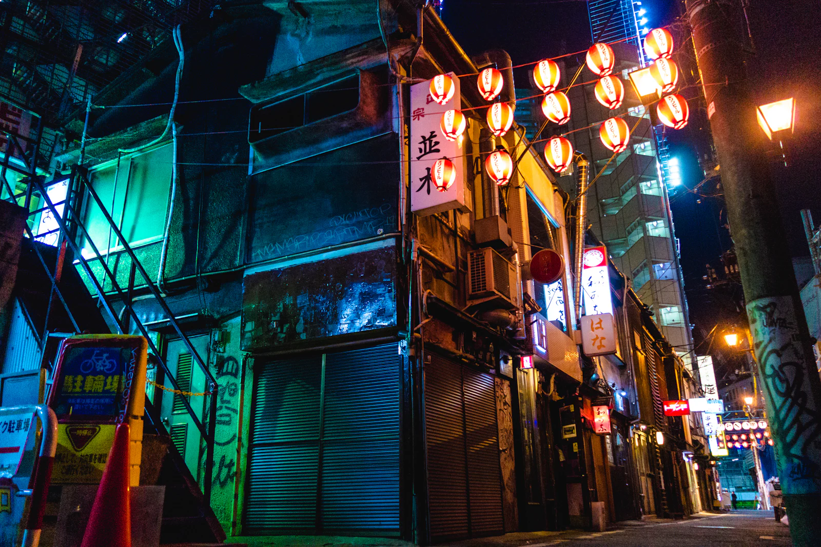 Red paper lanterns strung across a narrow alley at night.