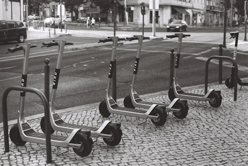 Electric scooters lined up on a city street ready for use.