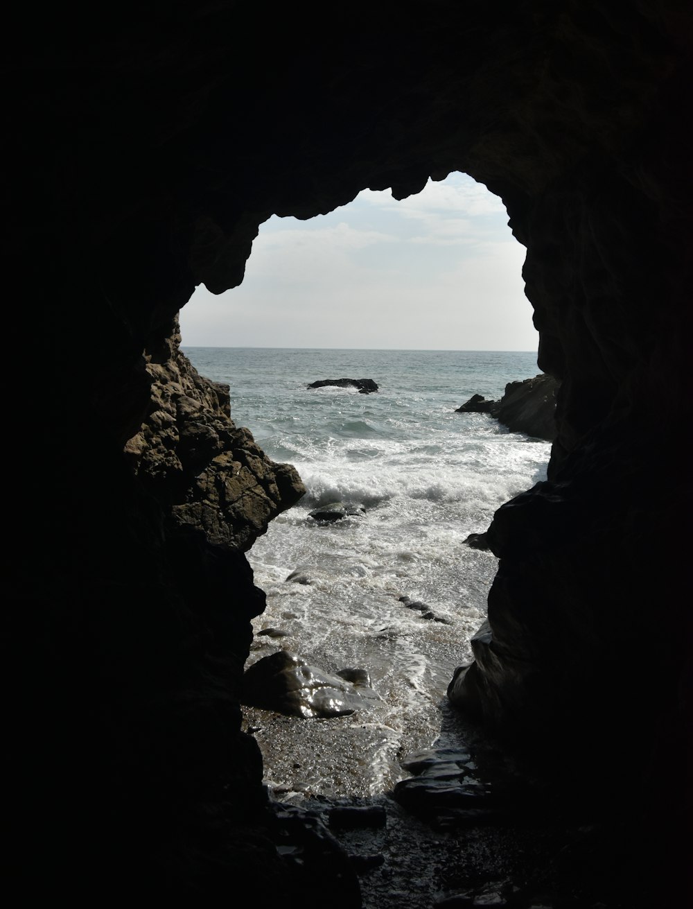 brown cave near body of water during daytime