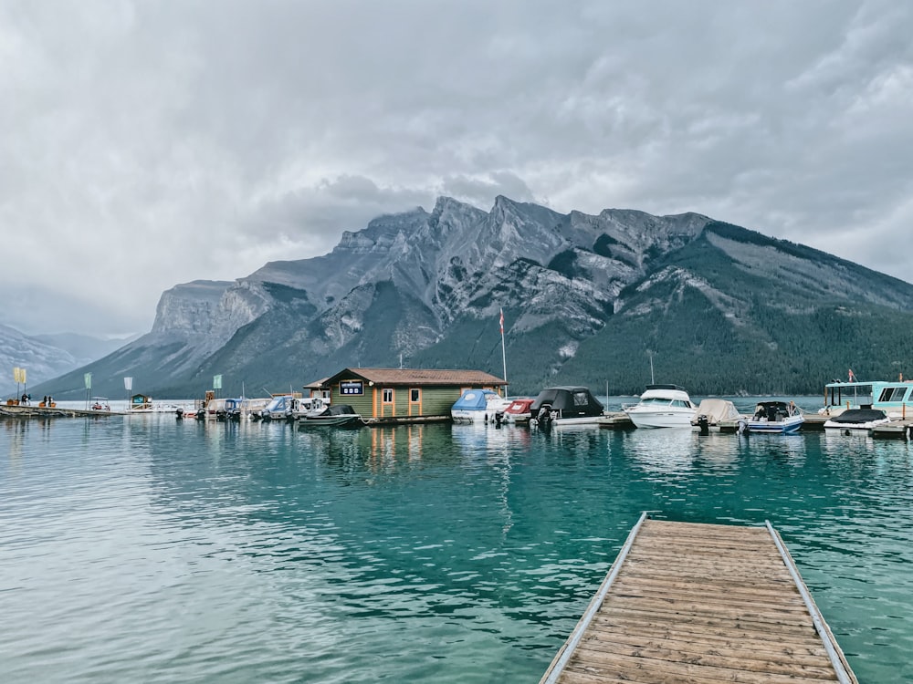 brown wooden dock on lake near mountain under white cloudy sky during daytime