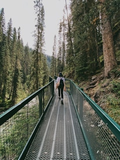 woman in black jacket walking on wooden bridge